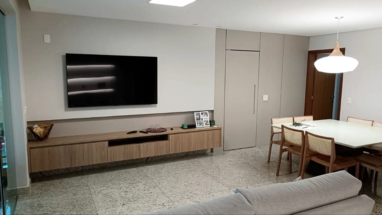Sala integrada com painel, rack e mesa de jantar planejada